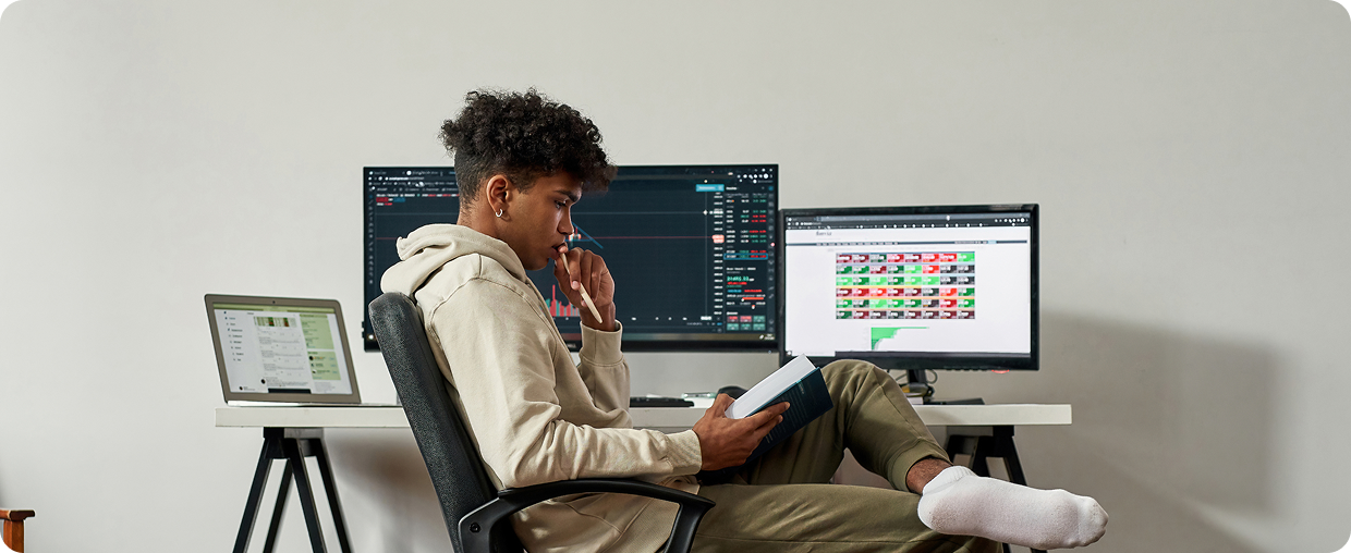 Person reading book at computer desk